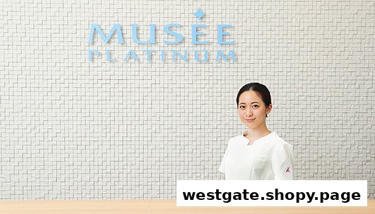 A friendly staff member stands in front of the Musee Platinum Tokyo branding wall.