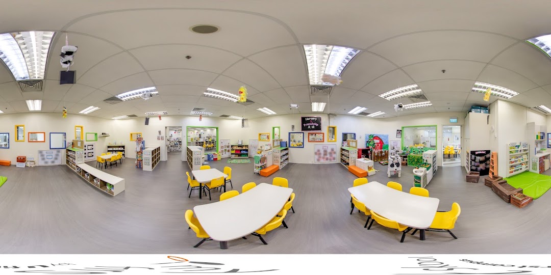 A bright, spacious interior of My First Skool, featuring colorful learning stations, tables, and chairs for young children.