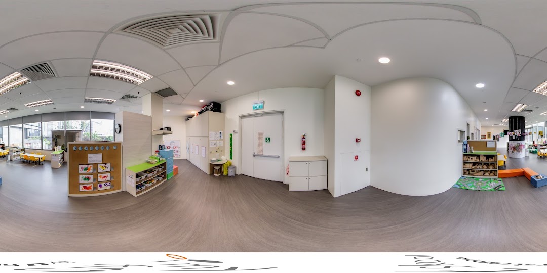 A bright, spacious interior of a childcare center featuring play areas, child-sized furniture, and an exit.