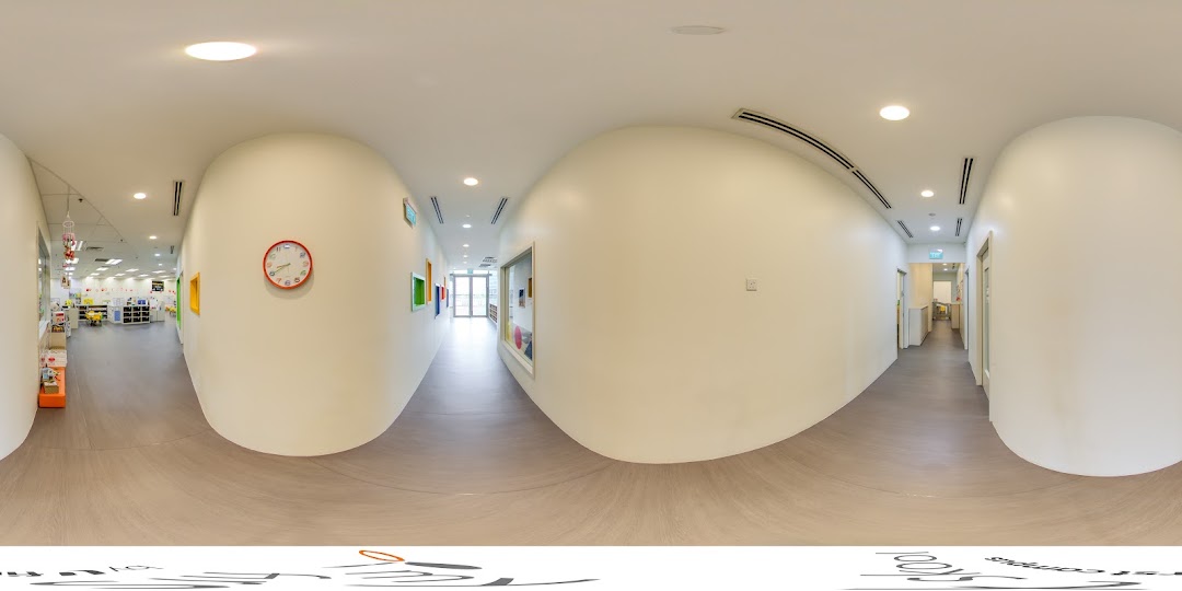 A bright, clean hallway inside My First Skool, featuring a clock and glimpses into learning spaces.