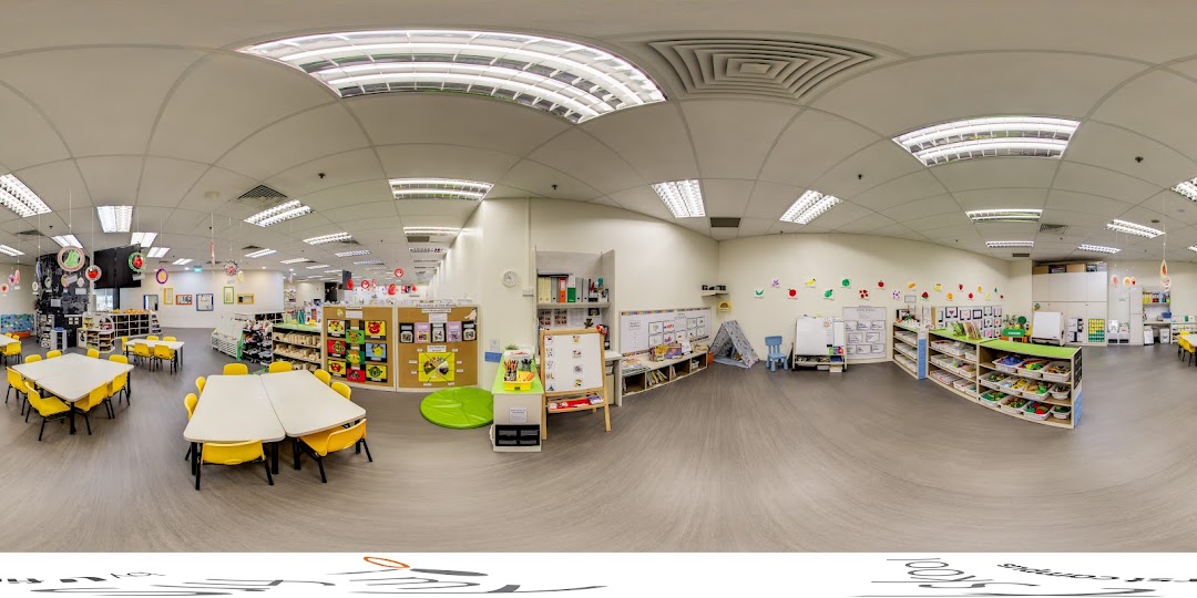 A wide-angle view of a bright, spacious classroom with colorful learning materials and child-sized furniture.