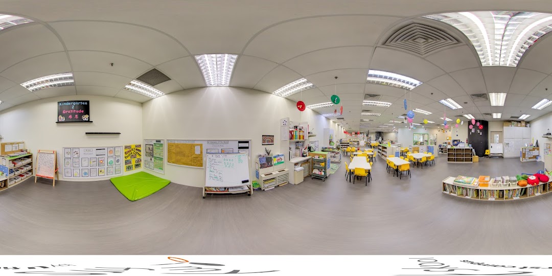A bright, spacious kindergarten classroom with colorful learning areas, child-sized tables, and educational displays.