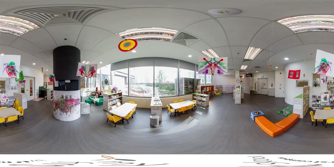A bright, spacious classroom interior at My First Skool, featuring children's art, tables, and play areas.