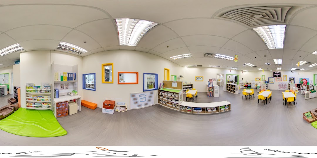 A bright and organized interior of a childcare center with play areas, tables, and learning materials.