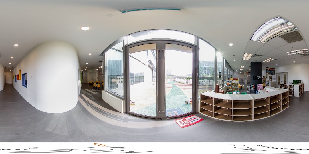 A bright, spacious interior of a childcare center with an outdoor play area visible through large windows.