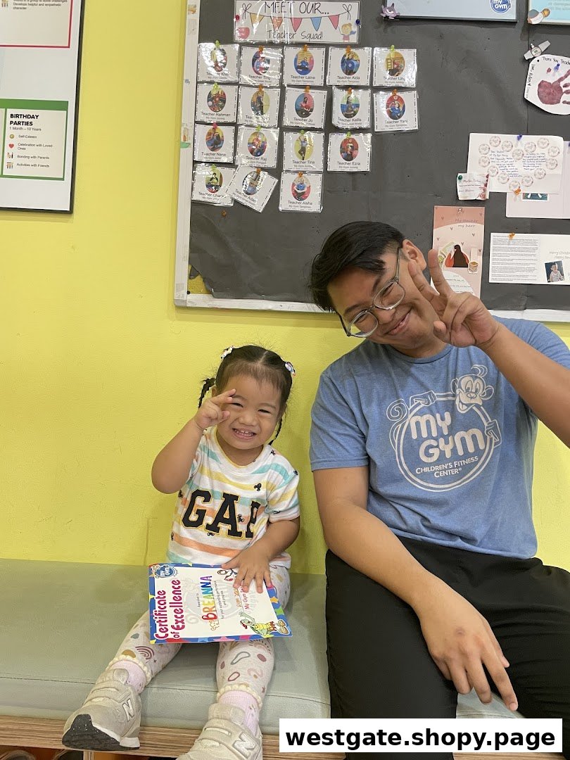 A happy child holding a certificate with a smiling adult in a My Gym Children's Fitness Center.