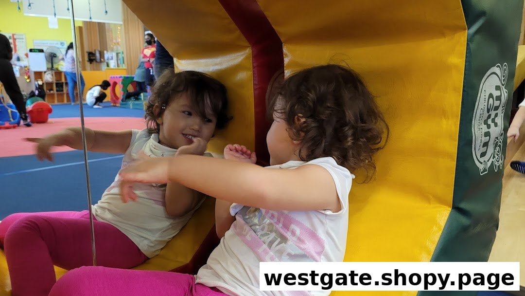 A young child smiles while interacting with a mirror in a vibrant children's fitness center.