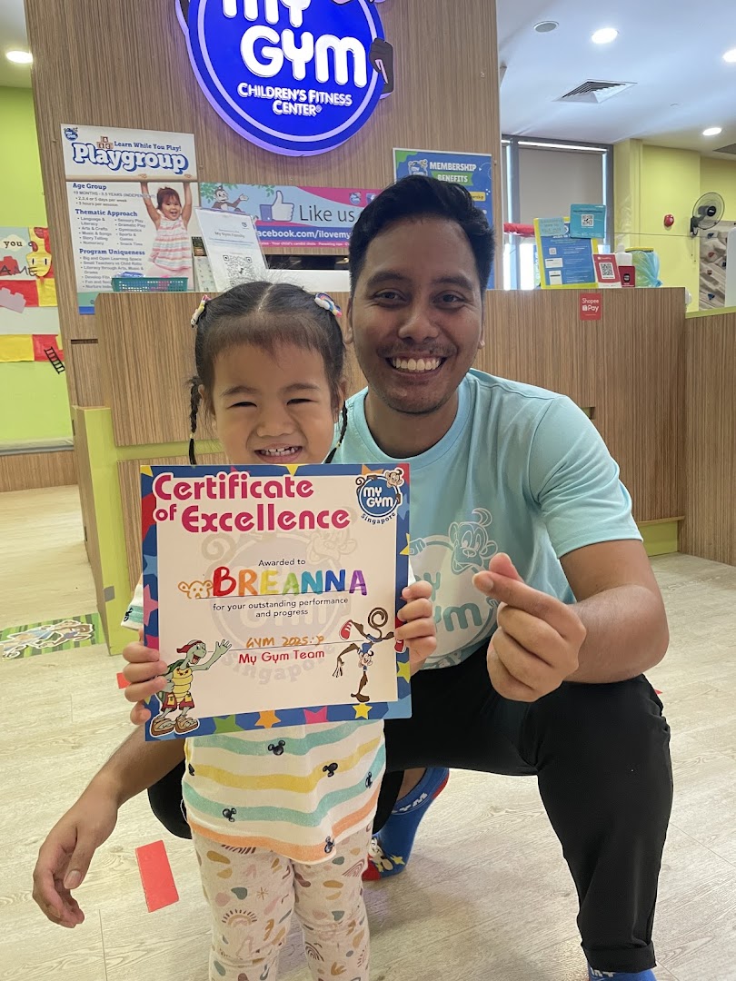 A happy child and adult proudly display a 'Certificate of Excellence' at My Gym Children's Fitness Center.