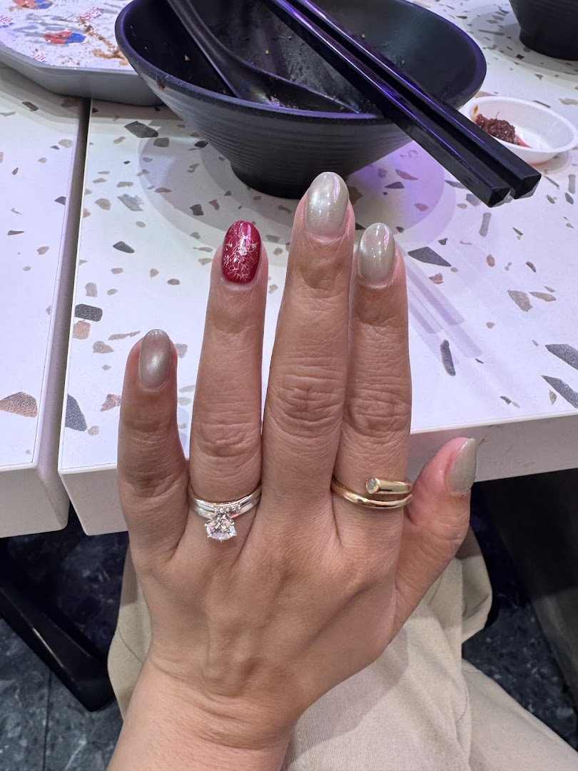 A hand showcasing freshly manicured nails with a red accent nail and light neutral colors.