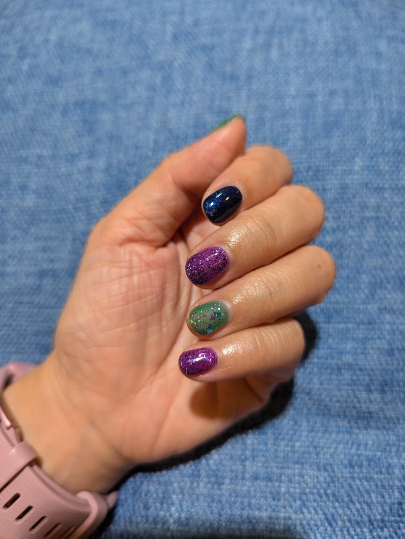 A hand showcasing vibrant, glittery nail polish in multiple colors.