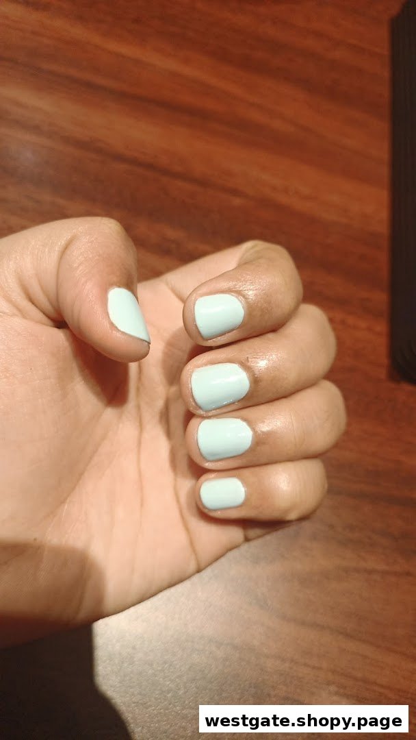 A hand showcasing light blue nail polish against a warm wooden background.