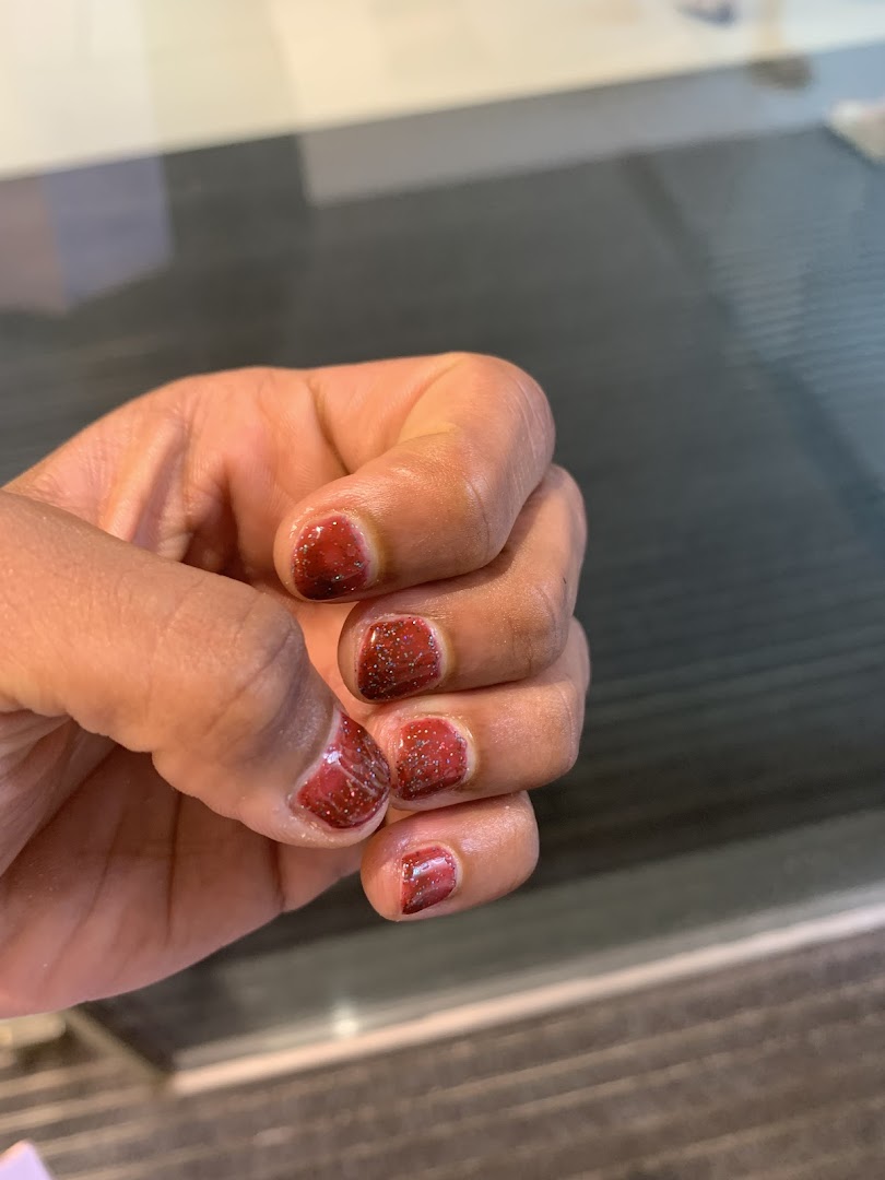 A hand showcasing freshly painted red glitter nails, highlighting a nail salon service.