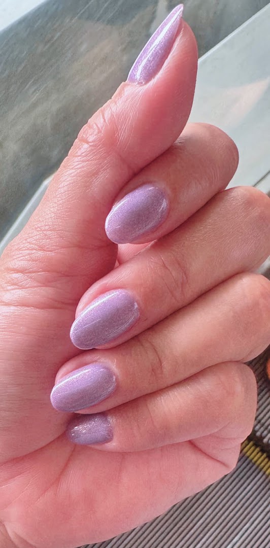A hand showcasing freshly painted, shimmery lavender nails with an oval shape.