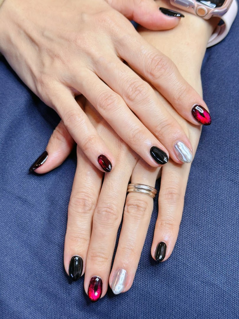 Close-up of hands showcasing a stylish manicure with black, silver, and red cat-eye nails.