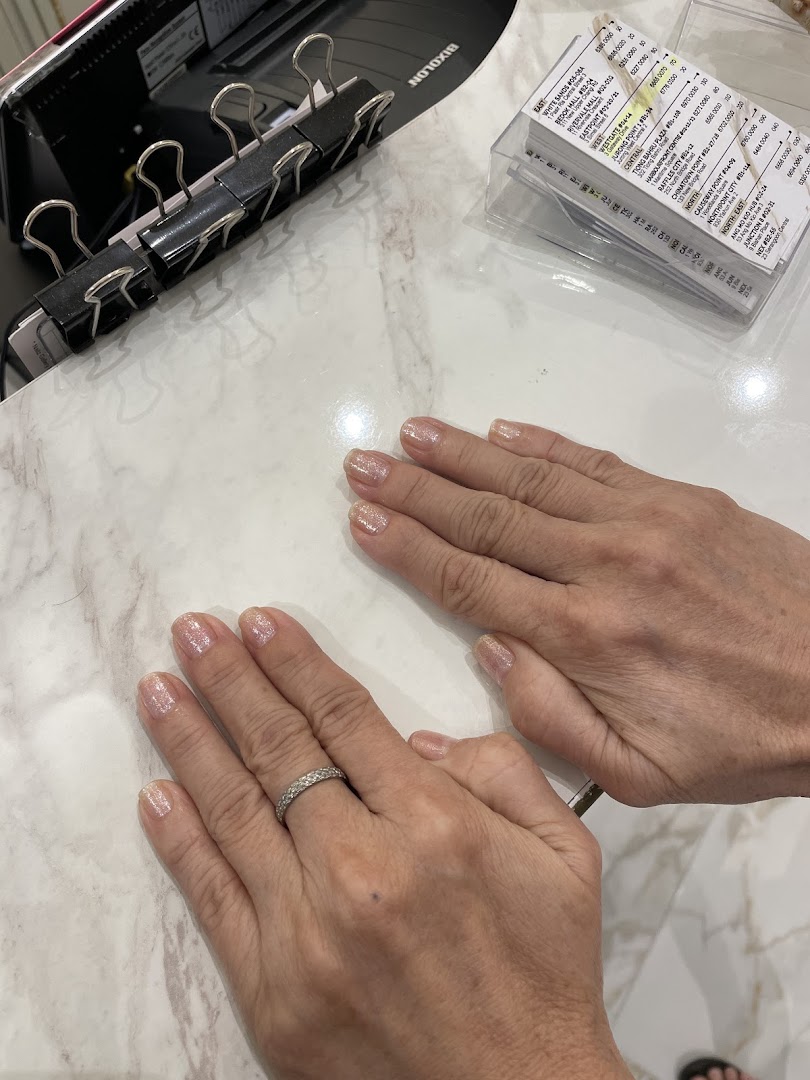 Hands with freshly manicured nails on a white marble-patterned table.
