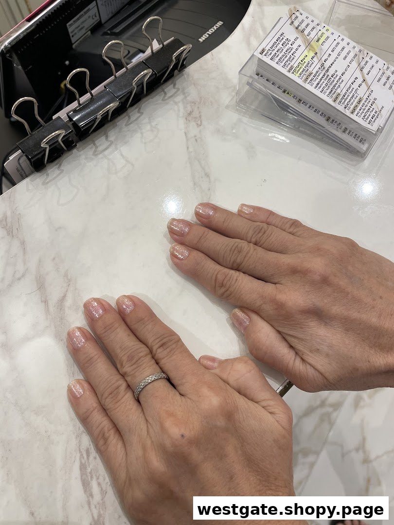 Hands with freshly manicured nails on a white marble-patterned table.