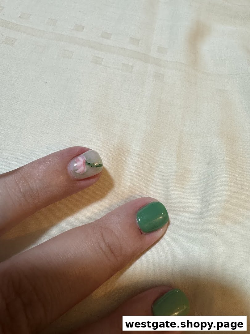 Close-up of fingers showcasing green and delicate floral nail art designs.