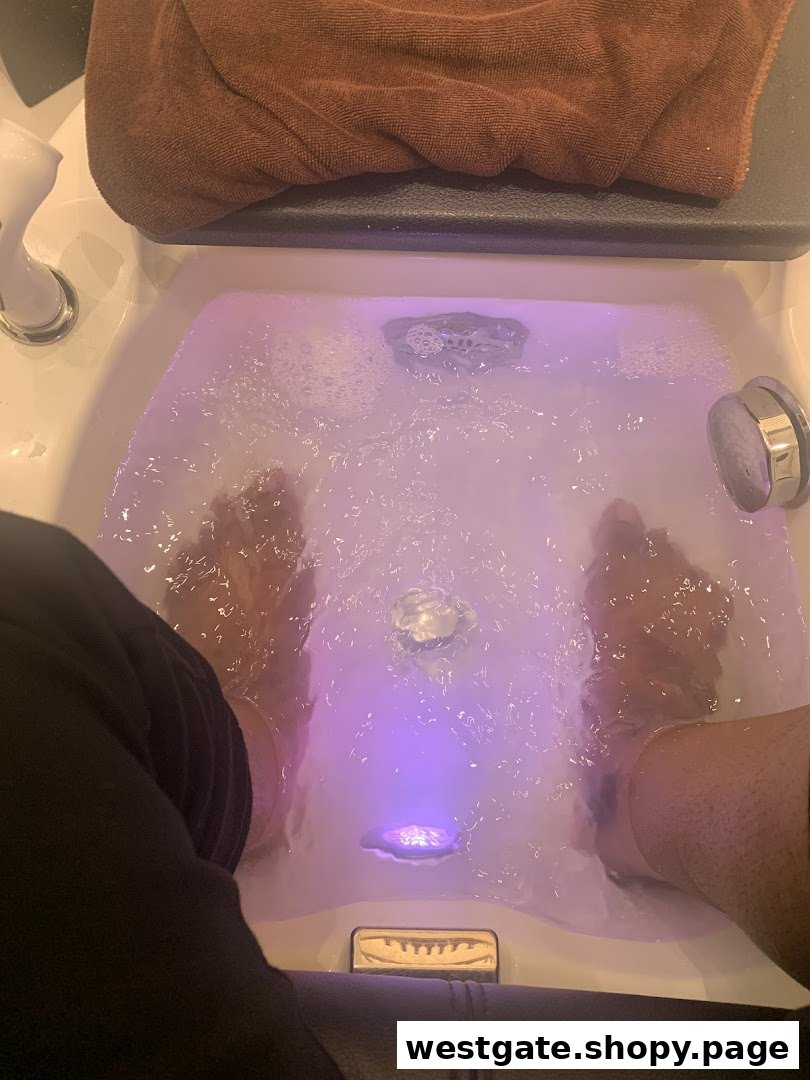 Feet soaking in a bubbling foot spa with purple light at Nailz Gallery.