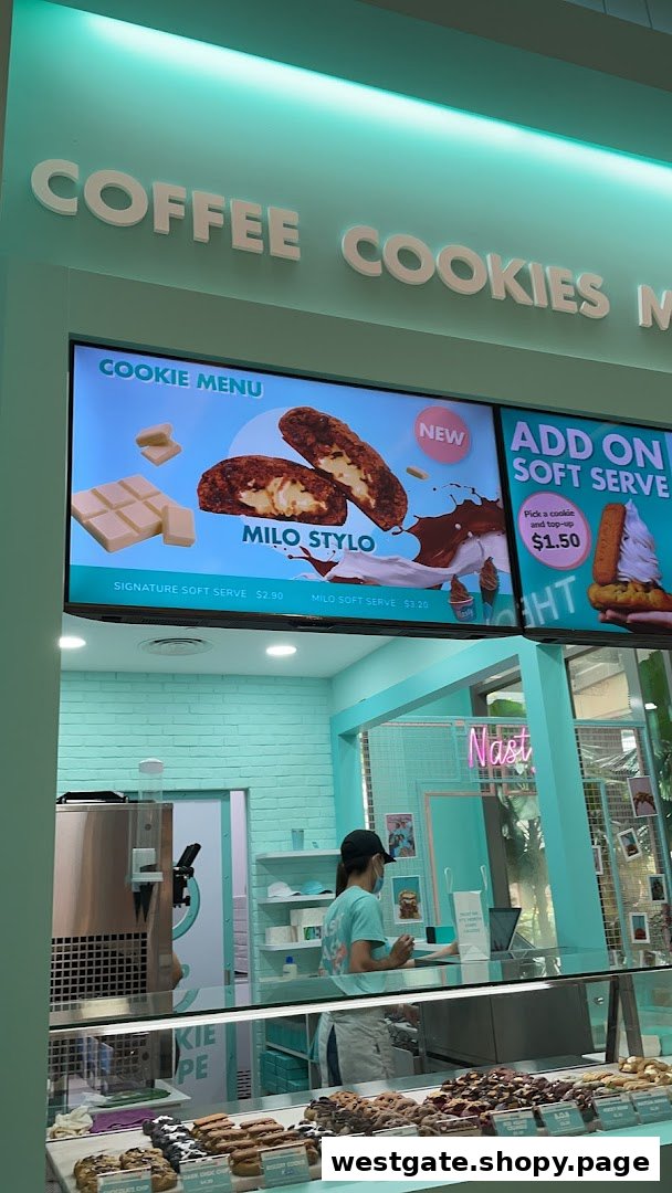 Interior view of Nasty Cookie - Westgate, showcasing the counter, staff, and digital menu boards.