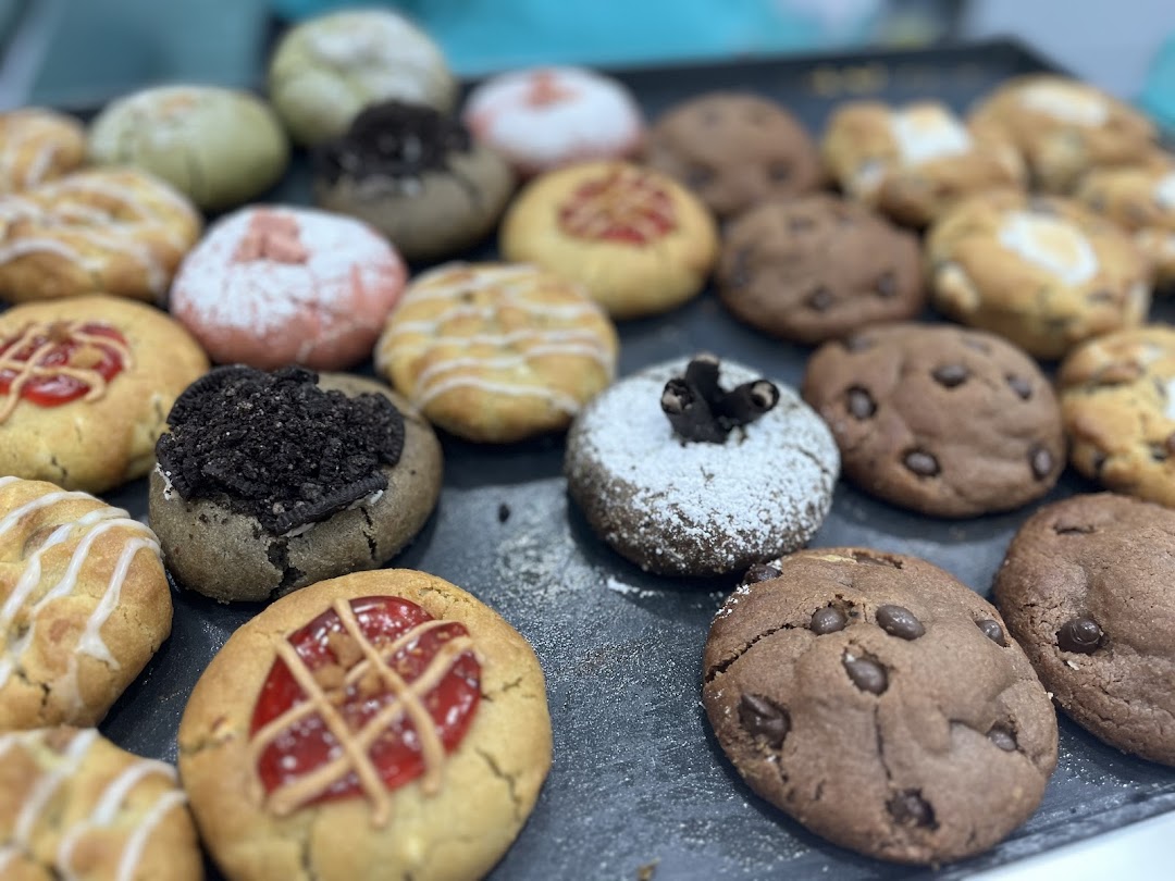 A close-up view of a tray filled with a variety of gourmet cookies, showcasing different flavors and toppings.