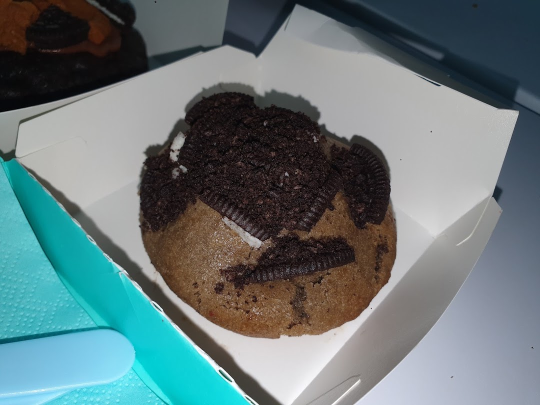 A delicious Nasty Cookie topped with Oreo crumbs and pieces in a white box.
