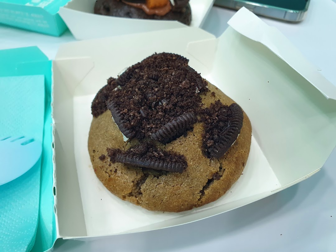 A delicious Nasty Cookie with Oreo pieces and crumbs in a white box.