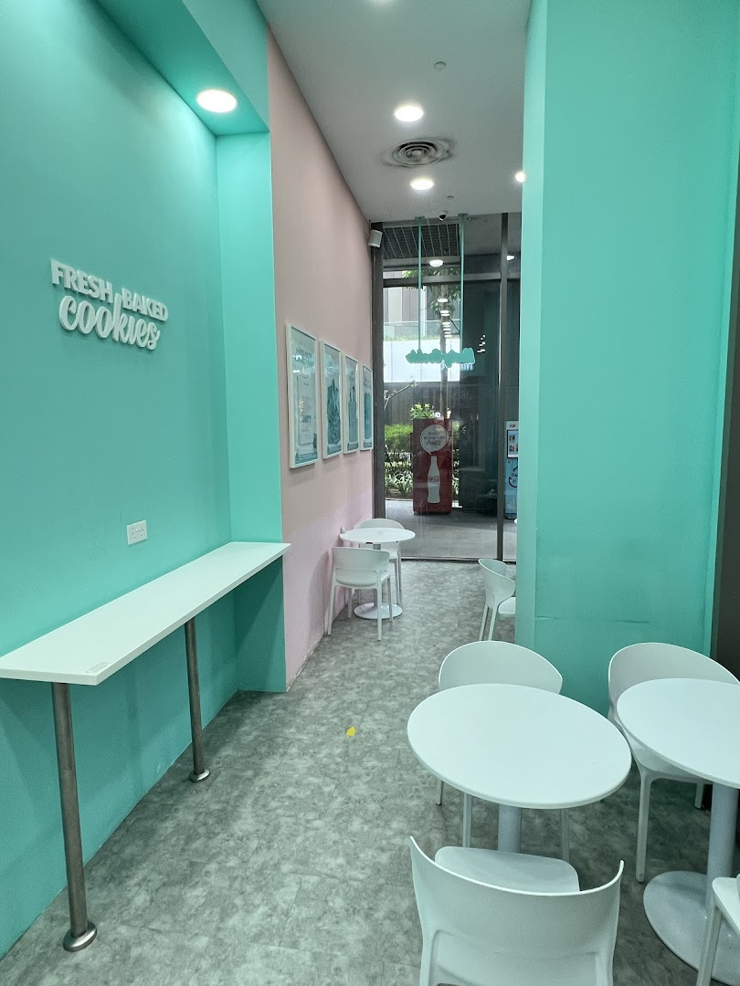A vibrant interior of Nasty Cookie with mint green and pink walls, featuring seating areas.