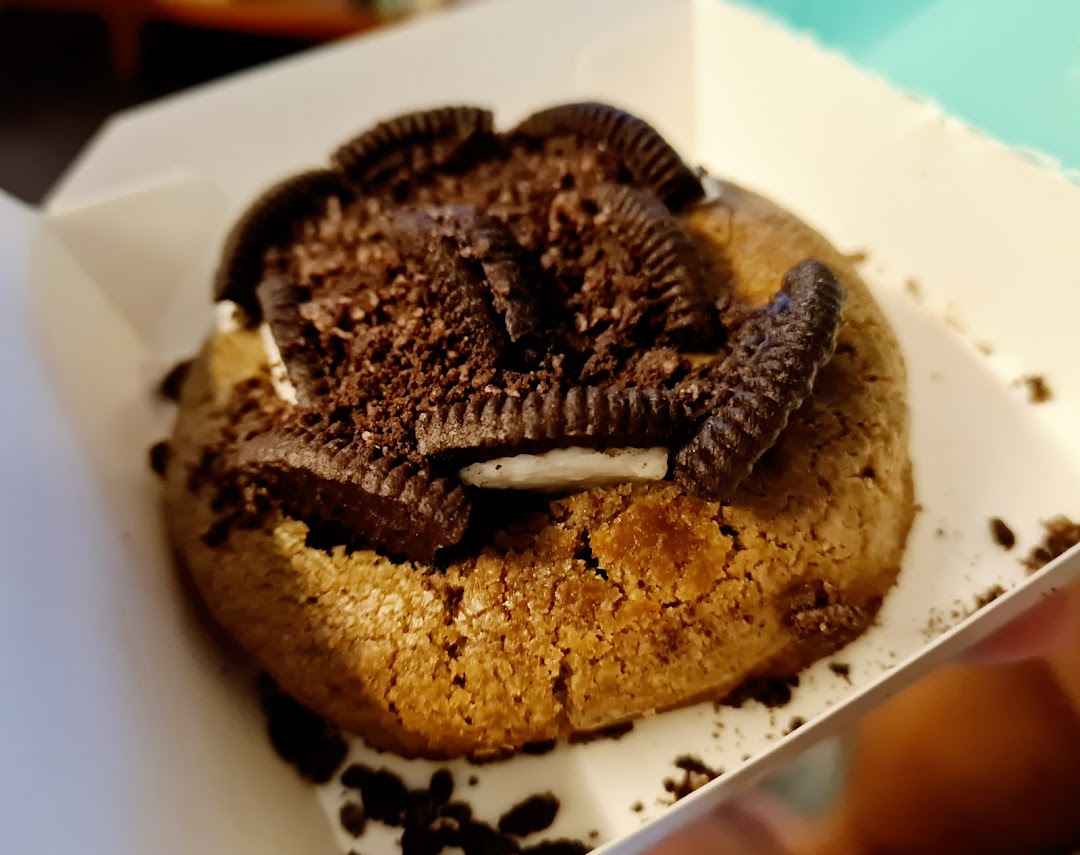 A close-up of a delicious Nasty Cookie topped with crushed Oreos and cookie pieces.