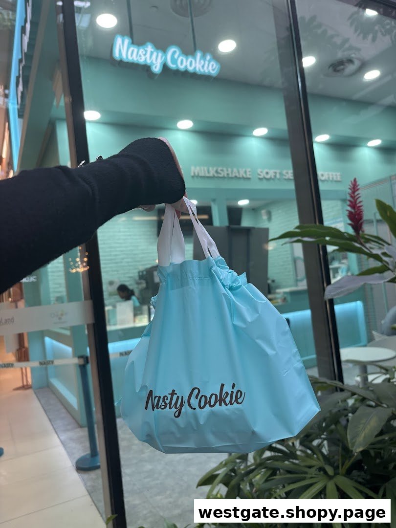 A person holds a Nasty Cookie bag outside the shop's teal-themed entrance.