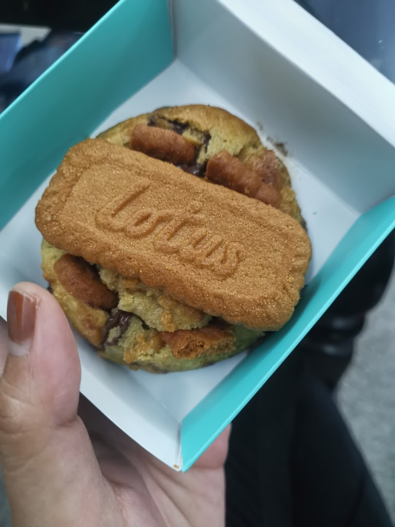 A hand holds a Nasty Cookie in a light blue box, featuring a Lotus Biscoff cookie on top.