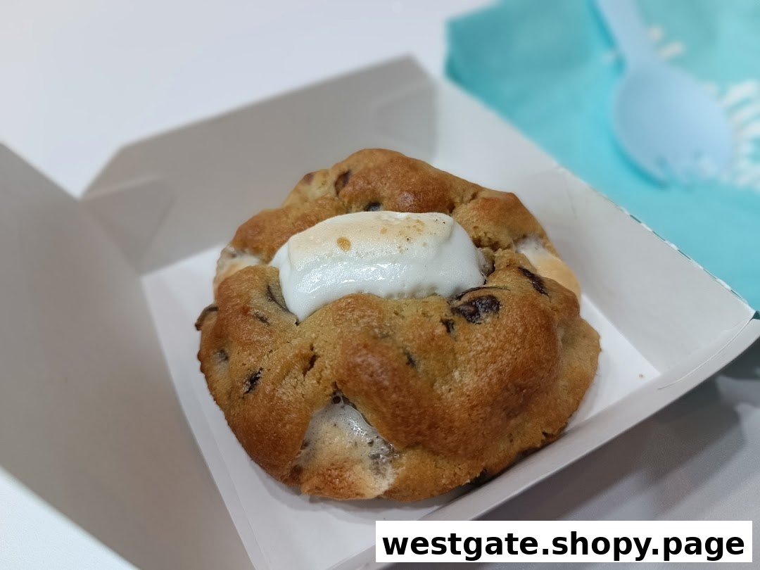 A close-up of a delicious chocolate chip cookie with a melted marshmallow center in a white box.