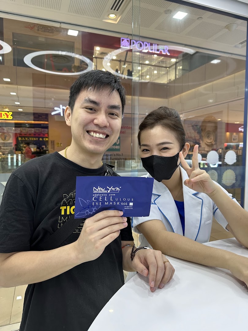 A man holds a New York Skin Solutions eye mask with a smiling staff member in a mall setting.