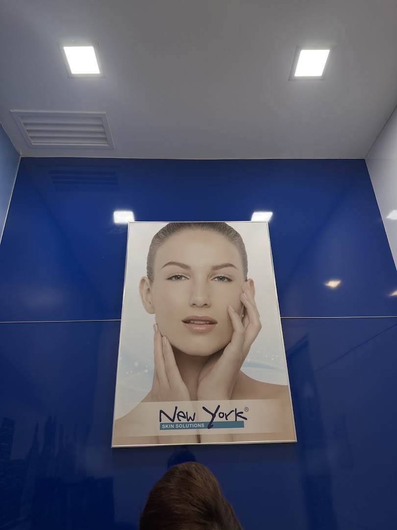 A large poster featuring a woman's face on a vibrant blue wall inside New York Skin Solutions.