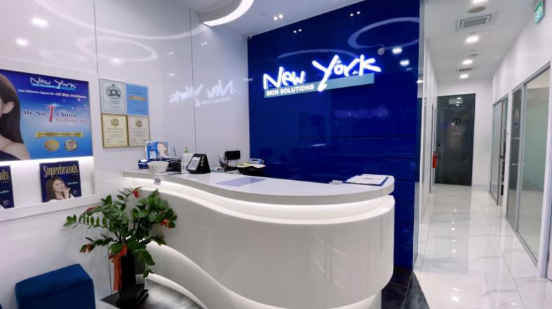 The bright and modern reception area of New York Skin Solutions, featuring a white desk and blue branding.