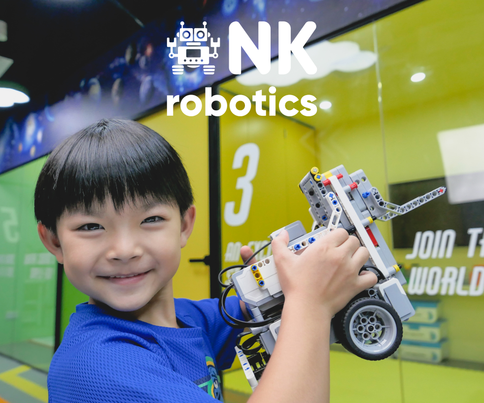 A smiling child holds a robot, showcasing the engaging learning experience at NK Robotics.