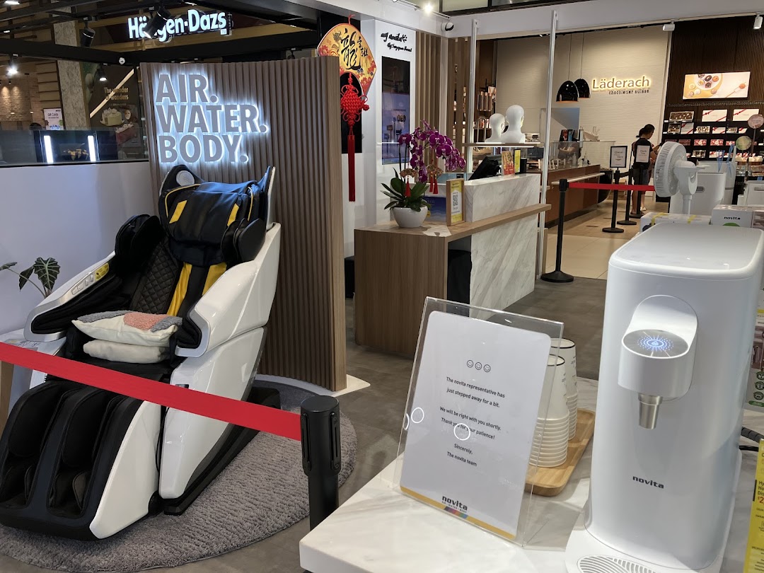 An interior view of novita Westgate, showcasing a massage chair and a water dispenser with a 'AIR. WATER. BODY.' display.