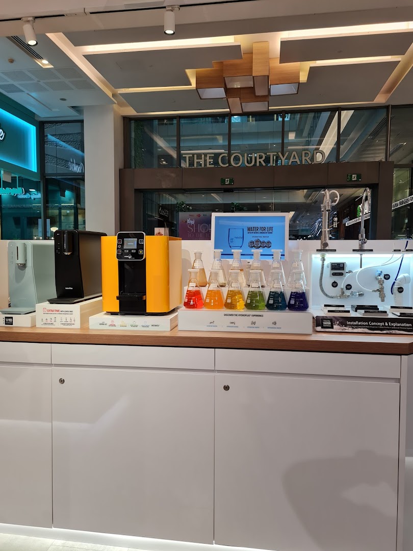 A retail display showcasing various water purifiers and related products, including colorful liquid samples.