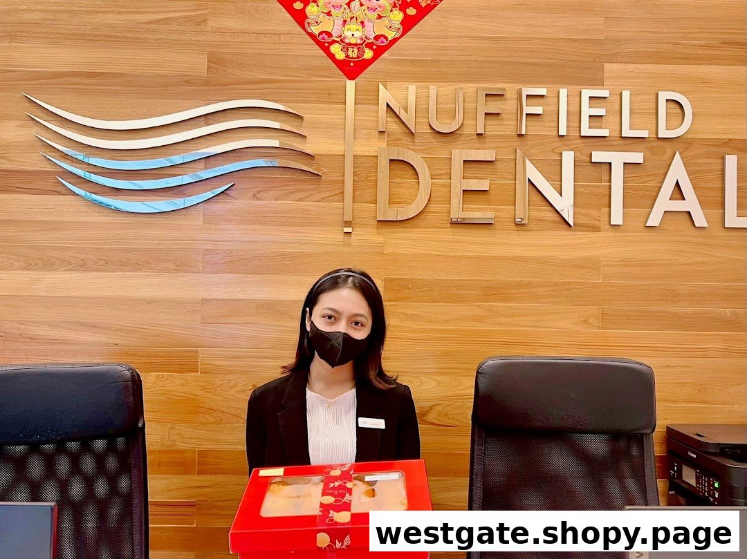 A masked staff member at the Nuffield Dental reception desk with the clinic's logo and name.