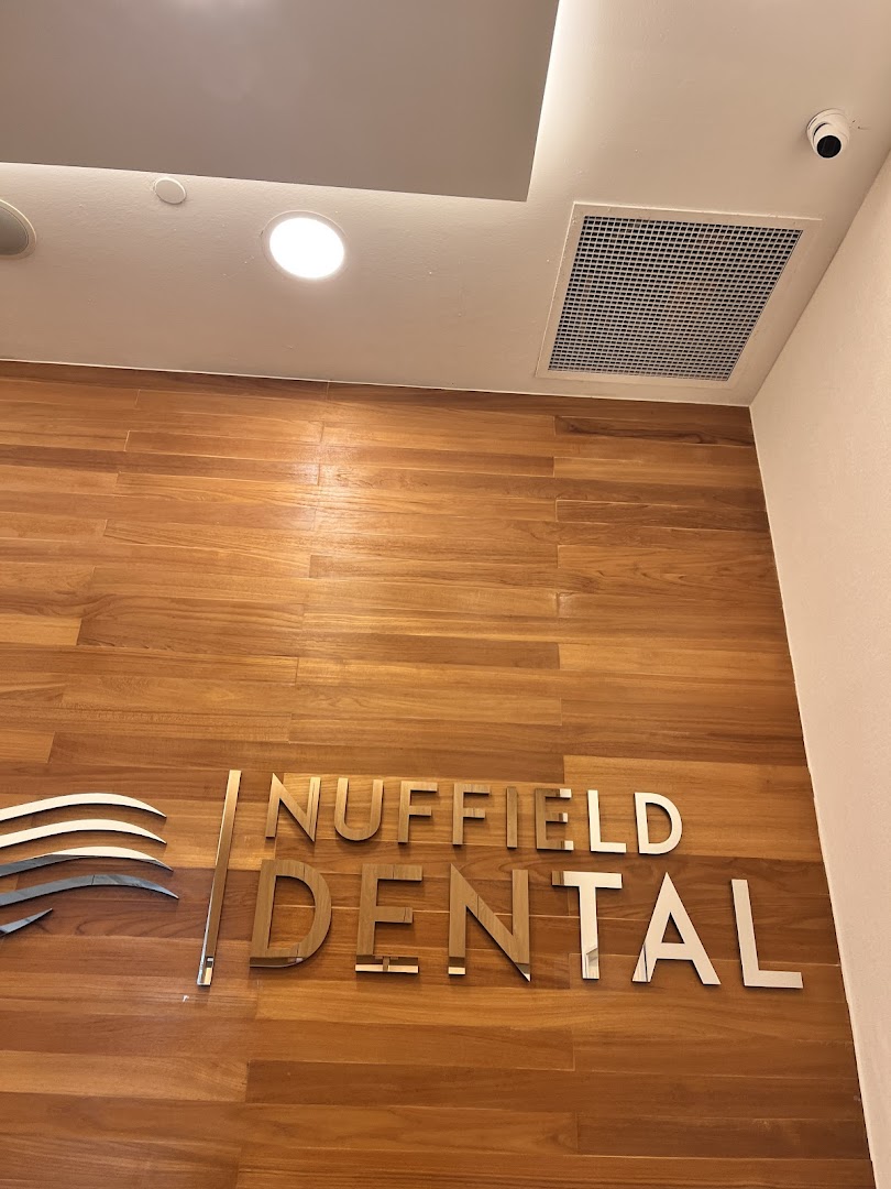 The image shows the Nuffield Dental logo and name on a modern wooden wall.
