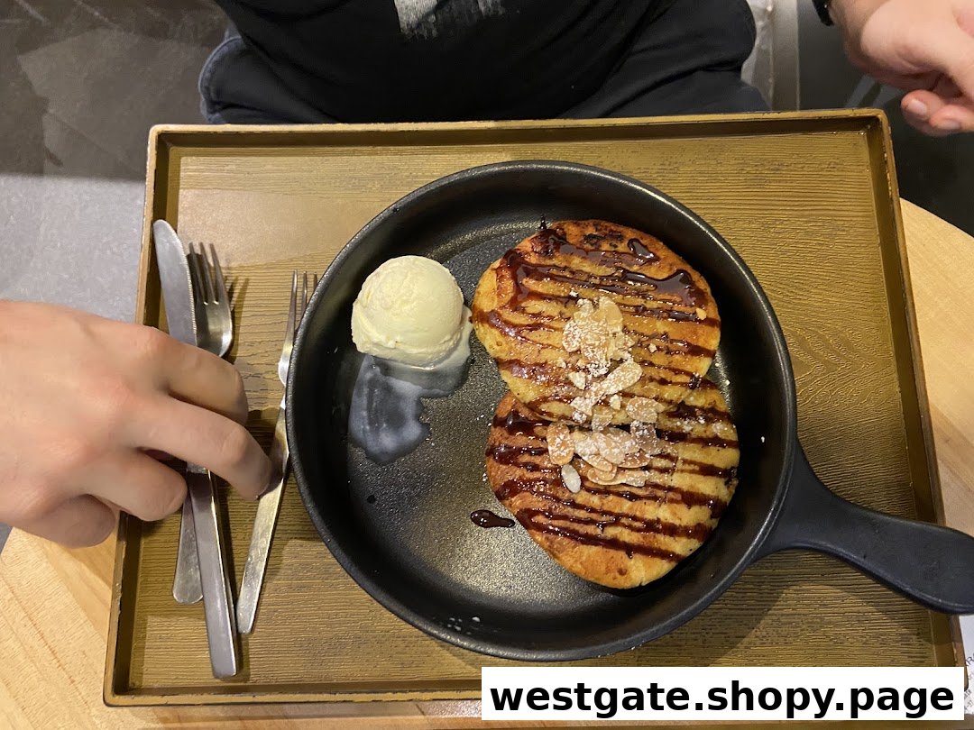 A delicious dessert featuring pancakes with chocolate drizzle, almonds, and a scoop of vanilla ice cream in a pan.