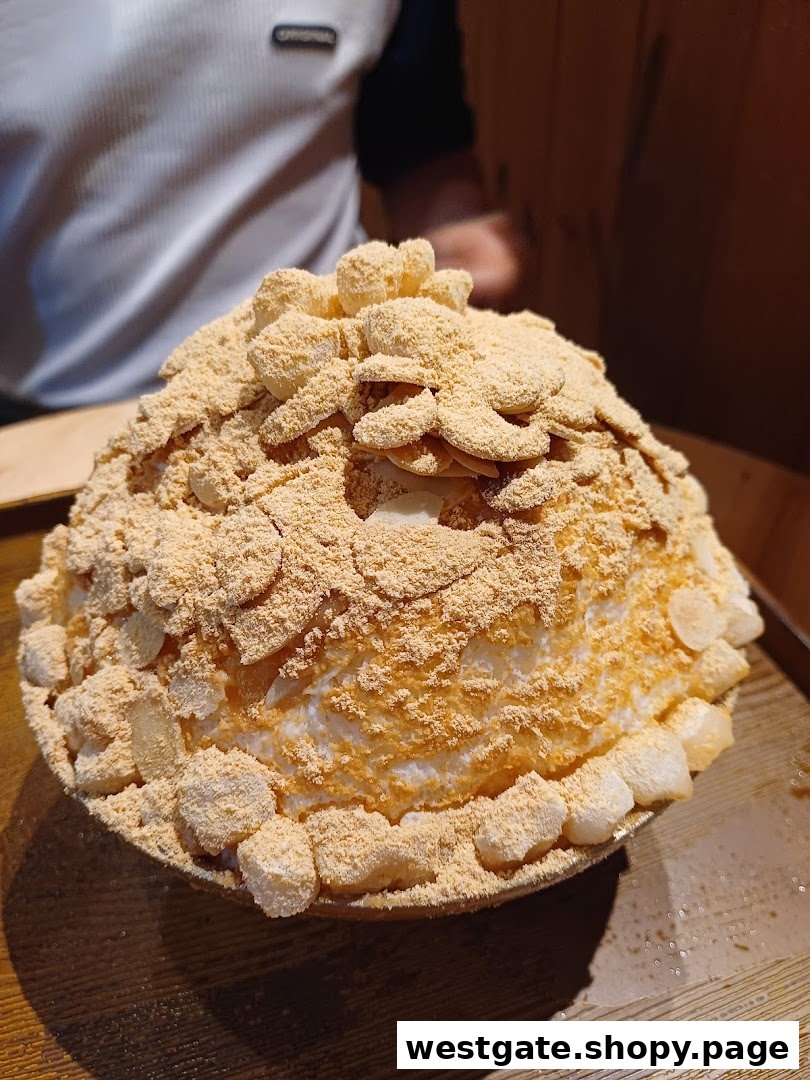 A close-up of a large Korean shaved ice dessert (bingsu) topped with kinako powder and rice cakes.