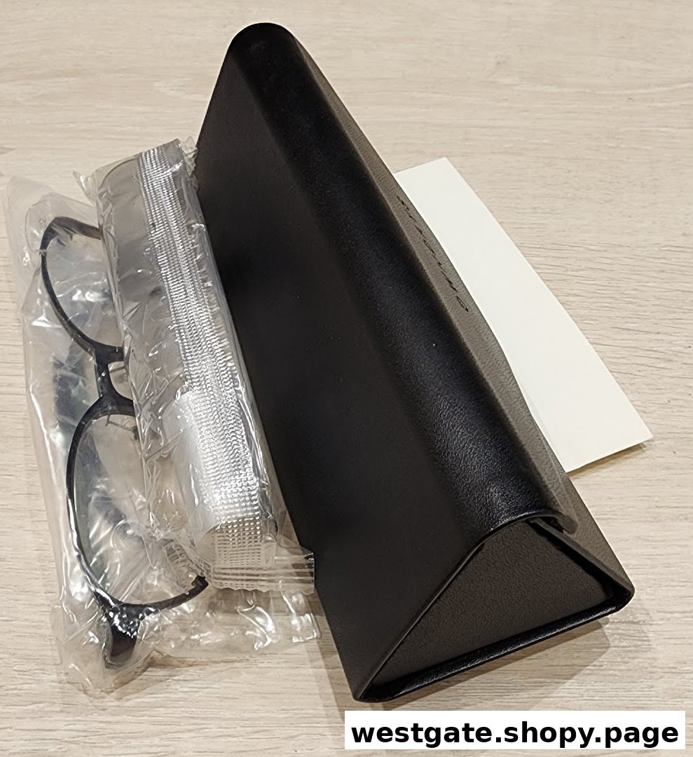 A new pair of eyeglasses in packaging with a case and cleaning cloth on a wooden surface.