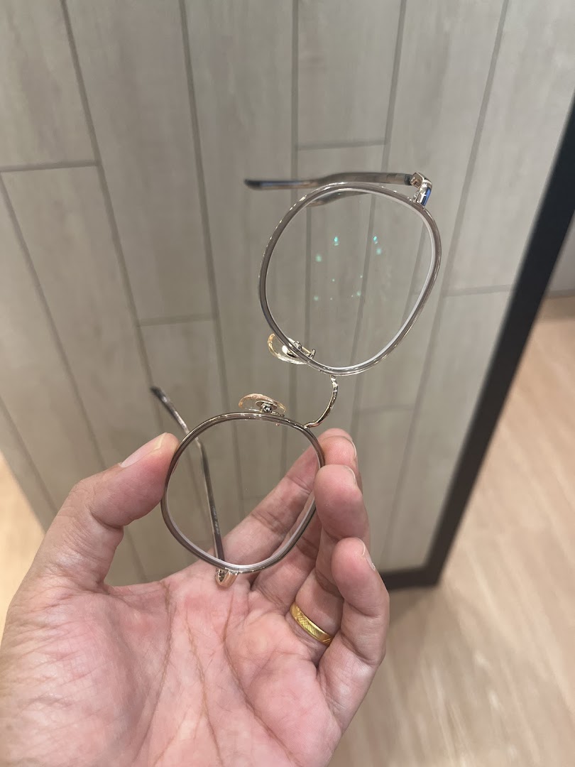 A hand holds a pair of stylish round eyeglasses, showcasing the frame's design.