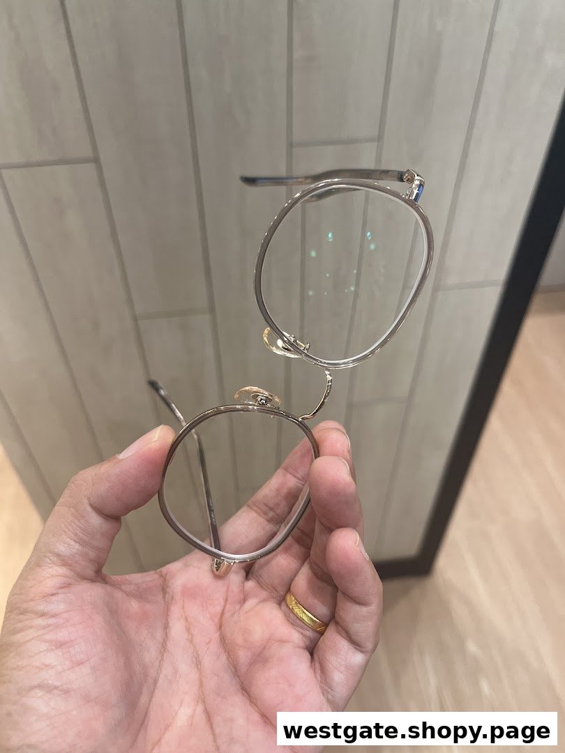 A hand holds a pair of stylish round eyeglasses, showcasing the frame's design.