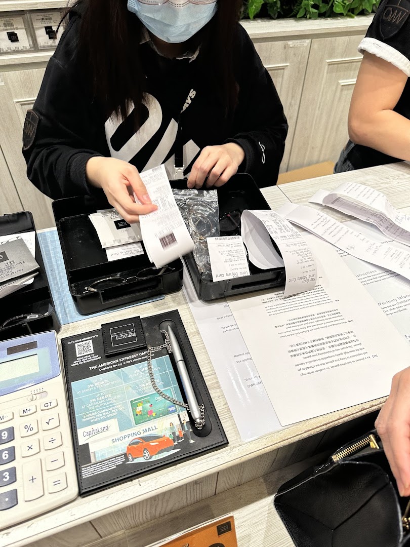 A customer completes a purchase at the OWNDAYS counter, handling receipts and eyewear.