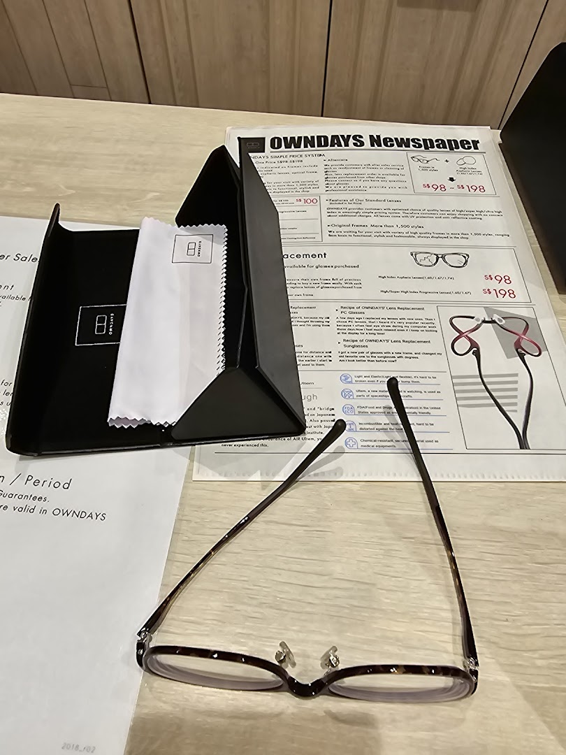 A pair of glasses, case, and an OWNDAYS Newspaper detailing pricing and services.