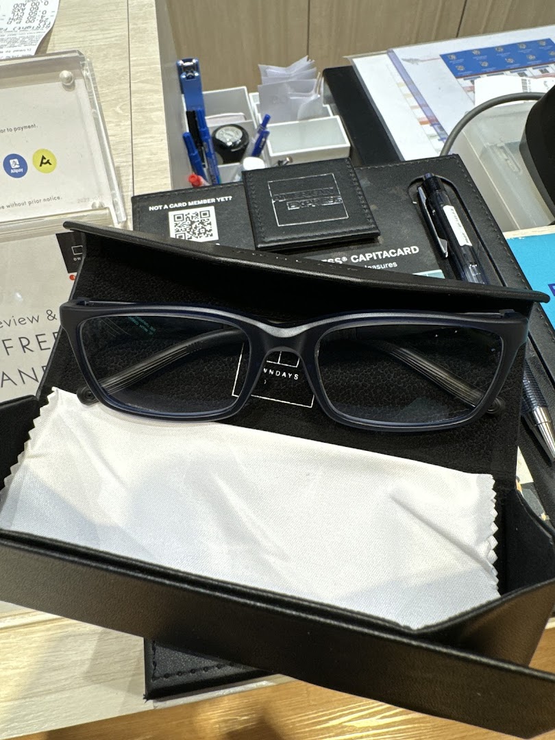 A pair of blue-framed glasses in a case with a cleaning cloth on a counter at OWNDAYS.