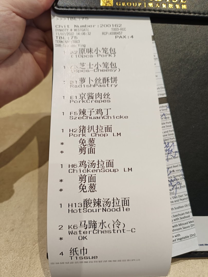 A close-up view of a dining order chit from Paradise Dynasty at Westgate, listing various dishes.
