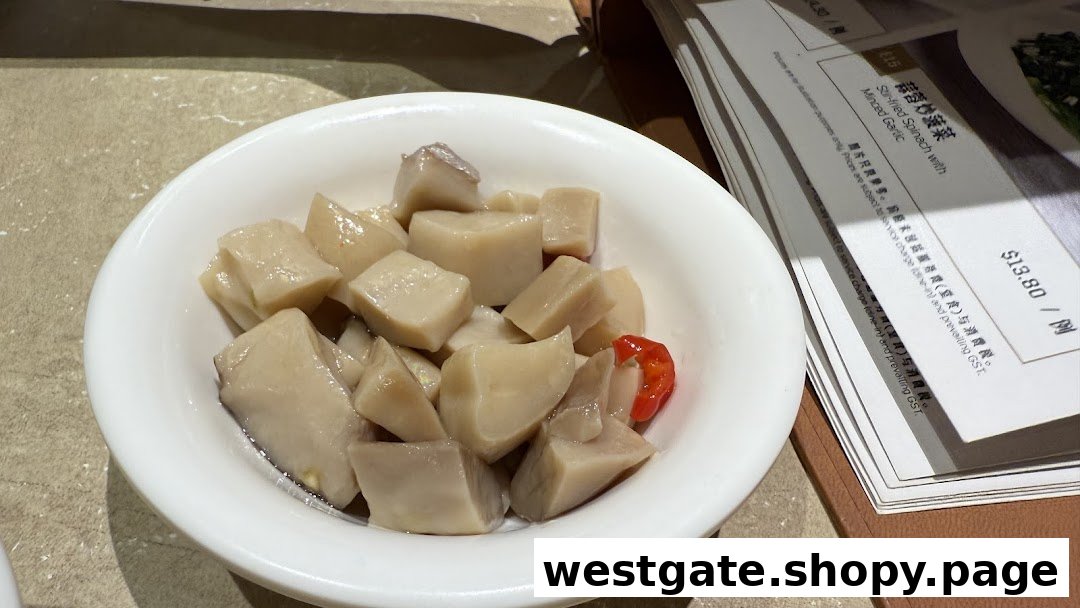 A bowl of braised cubed vegetables with a red chili, next to a menu displaying Stir-fried Spinach.