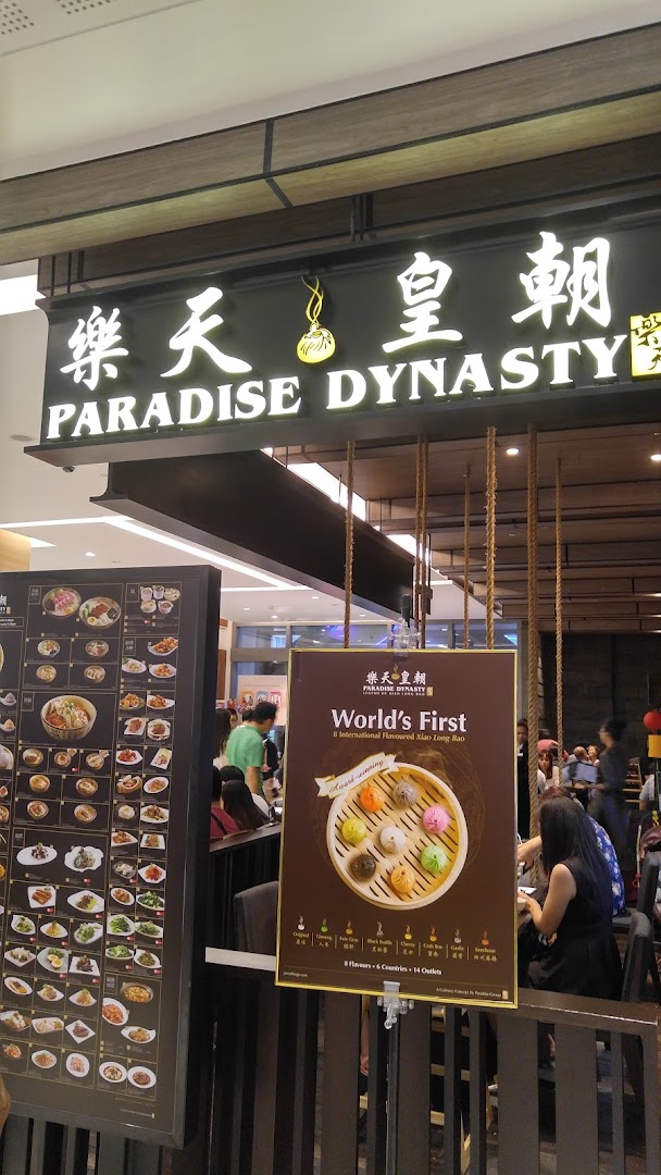 The entrance of Paradise Dynasty restaurant, featuring its prominent signage and promotional displays for its signature Xiao Long Bao.